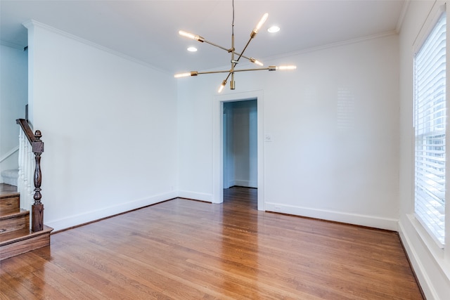 unfurnished room with crown molding, light hardwood / wood-style flooring, a healthy amount of sunlight, and a notable chandelier