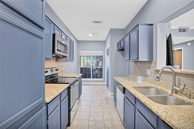 kitchen featuring light stone counters, sink, appliances with stainless steel finishes, and tasteful backsplash