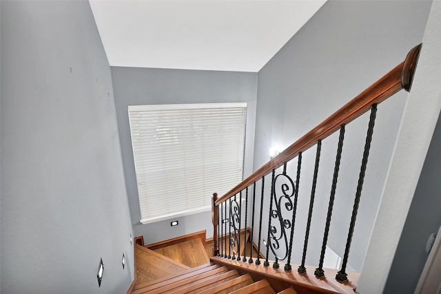 staircase with hardwood / wood-style floors and vaulted ceiling