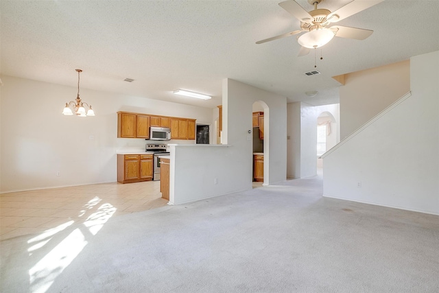 kitchen with a textured ceiling, decorative light fixtures, appliances with stainless steel finishes, light colored carpet, and ceiling fan with notable chandelier