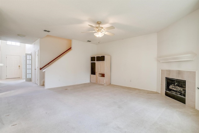 unfurnished living room featuring a tile fireplace, light carpet, and ceiling fan