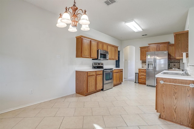 kitchen featuring light tile patterned flooring, stainless steel appliances, decorative light fixtures, sink, and a notable chandelier