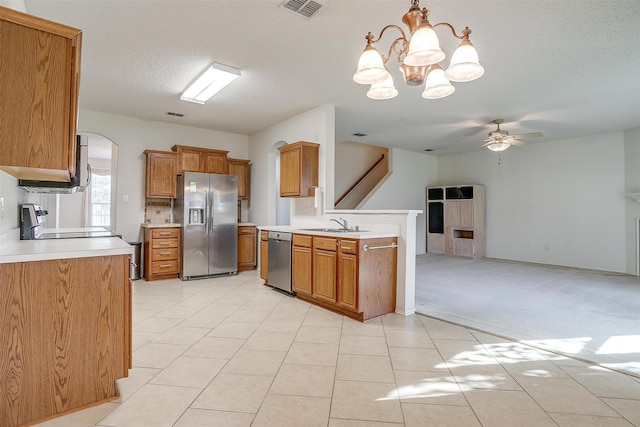 kitchen with a textured ceiling, ceiling fan with notable chandelier, appliances with stainless steel finishes, light tile patterned floors, and decorative light fixtures