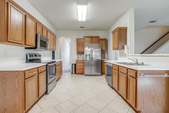 kitchen with stainless steel appliances, a textured ceiling, light tile patterned floors, and sink