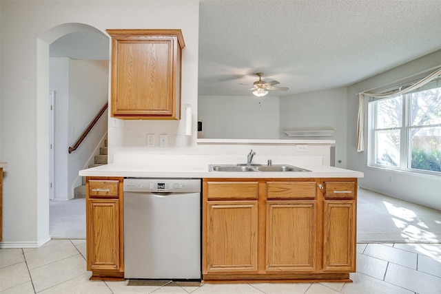 kitchen with light tile patterned floors, a textured ceiling, ceiling fan, stainless steel dishwasher, and sink