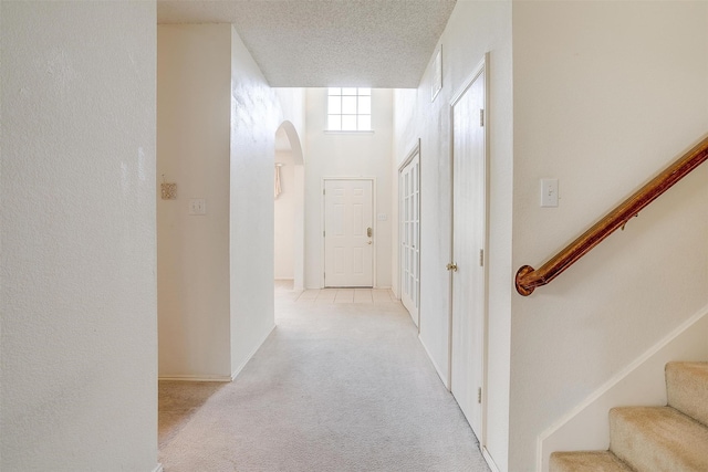 hall featuring light carpet and a textured ceiling