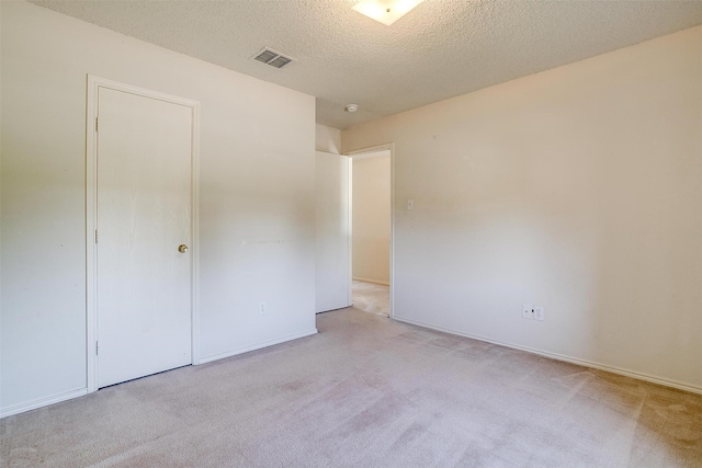 unfurnished bedroom with light colored carpet, a textured ceiling, and a closet