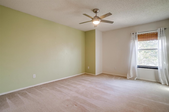 spare room with light carpet, ceiling fan, and a textured ceiling