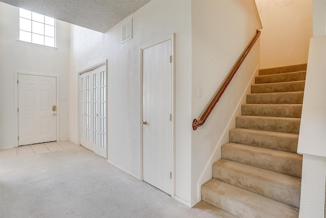 carpeted foyer with a textured ceiling and a towering ceiling