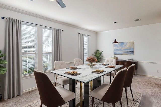 dining space featuring a healthy amount of sunlight, ornamental molding, and light colored carpet