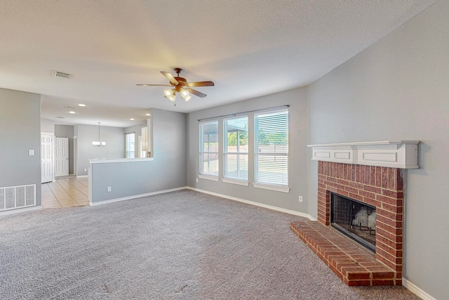 unfurnished living room featuring a textured ceiling, a fireplace, ceiling fan, and light colored carpet