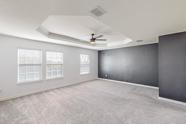 carpeted empty room featuring crown molding, a tray ceiling, and ceiling fan