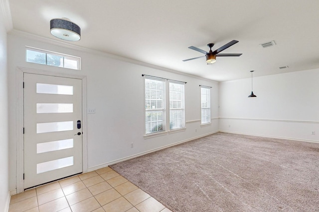 entrance foyer featuring ornamental molding, ceiling fan, light colored carpet, and a wealth of natural light