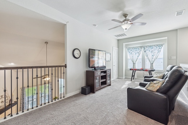 living room with ceiling fan, light colored carpet, and a textured ceiling