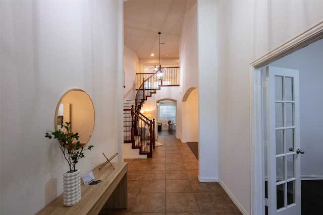 hallway with a towering ceiling and dark tile patterned floors