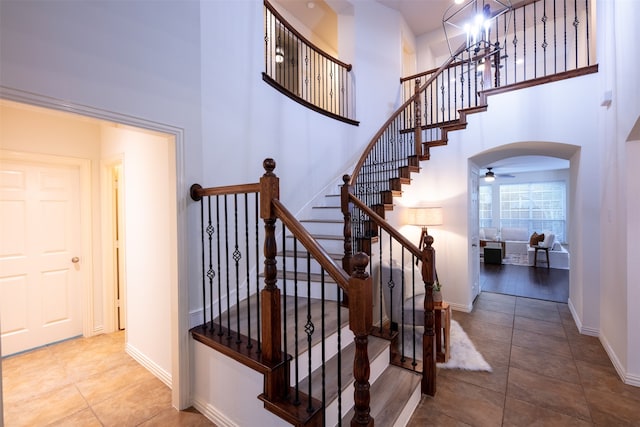 staircase featuring a towering ceiling, wood-type flooring, and ceiling fan