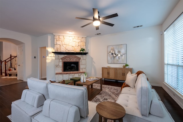 living room featuring ceiling fan, a fireplace, dark wood-type flooring, and a wealth of natural light