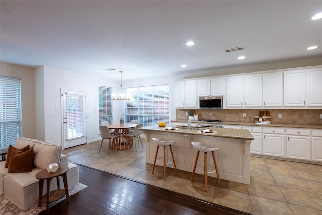 kitchen featuring pendant lighting, an island with sink, white cabinets, and light hardwood / wood-style floors