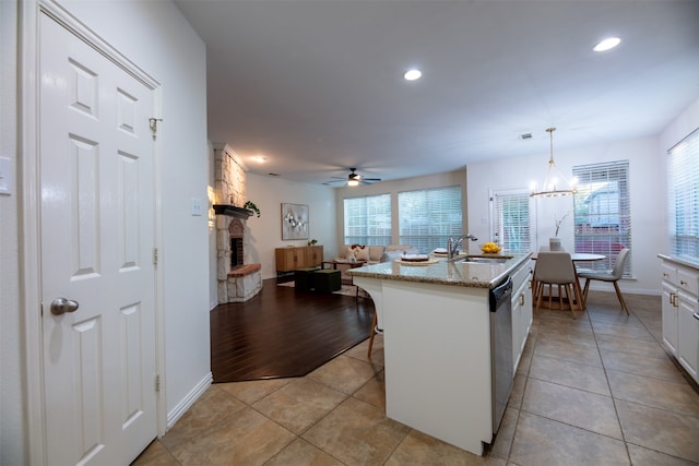 kitchen with white cabinets, pendant lighting, sink, a center island with sink, and light wood-type flooring