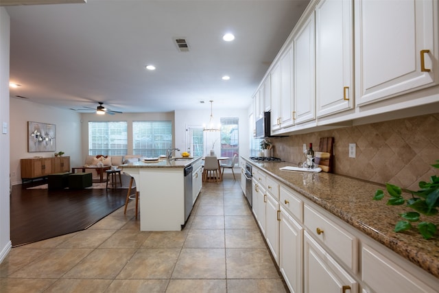 kitchen featuring white cabinets, an island with sink, decorative light fixtures, and a kitchen breakfast bar