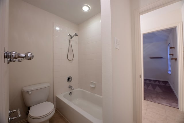 bathroom featuring tile patterned flooring, tiled shower / bath combo, and toilet