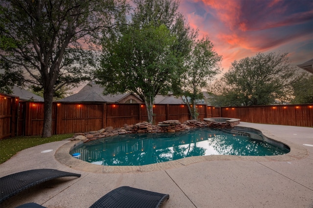 pool at dusk featuring a patio and an in ground hot tub