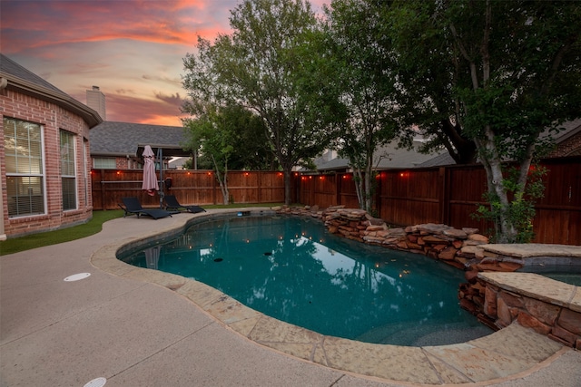 pool at dusk with a patio and an in ground hot tub