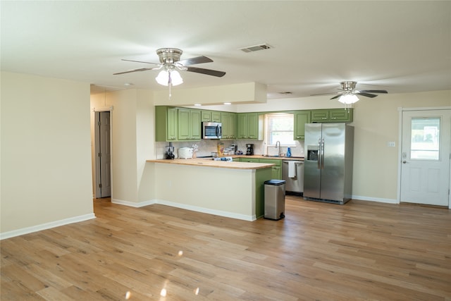 kitchen featuring kitchen peninsula, green cabinets, a healthy amount of sunlight, and stainless steel appliances