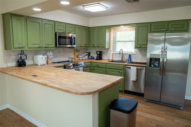 kitchen featuring green cabinets, kitchen peninsula, appliances with stainless steel finishes, and sink