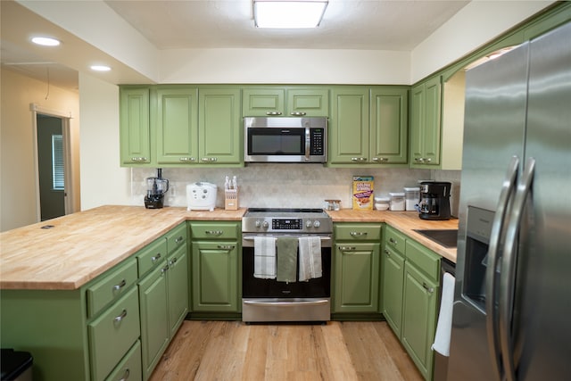 kitchen featuring kitchen peninsula, green cabinets, light hardwood / wood-style floors, and stainless steel appliances