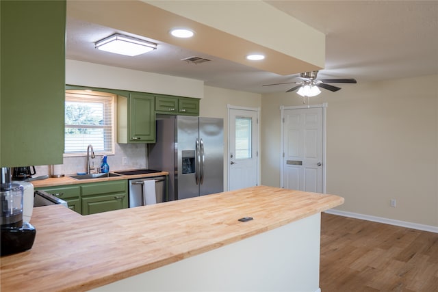 kitchen featuring sink, appliances with stainless steel finishes, green cabinetry, light hardwood / wood-style flooring, and wood counters