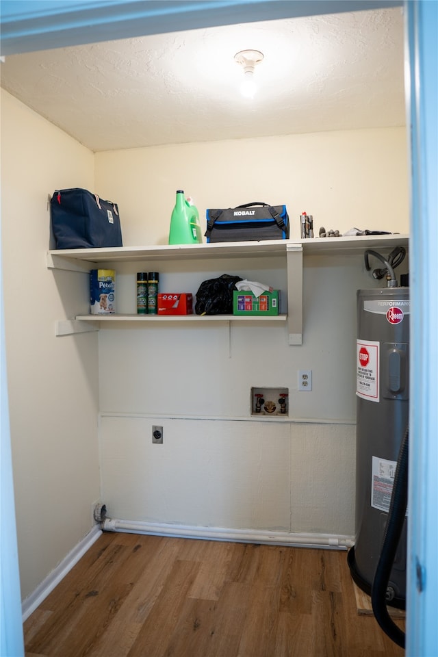 laundry room featuring hookup for a washing machine, water heater, dark hardwood / wood-style floors, and electric dryer hookup