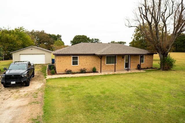 single story home featuring a front lawn, a garage, and an outbuilding