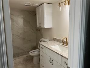 bathroom featuring walk in shower, vanity, and toilet