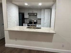 kitchen with black fridge, kitchen peninsula, stainless steel electric stove, and dark wood-type flooring