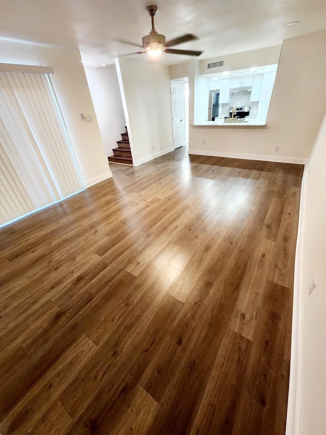 unfurnished living room featuring ceiling fan and hardwood / wood-style floors