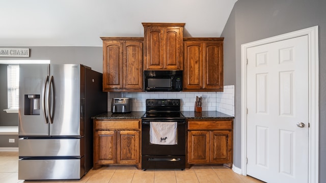 kitchen with vaulted ceiling, tasteful backsplash, light tile patterned floors, black appliances, and dark stone counters