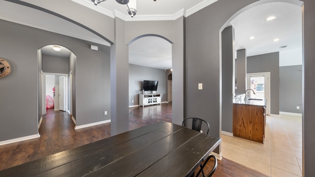 dining area with wood-type flooring, crown molding, and sink