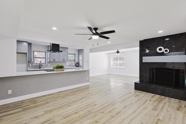 unfurnished living room with light wood-type flooring, ceiling fan, and plenty of natural light