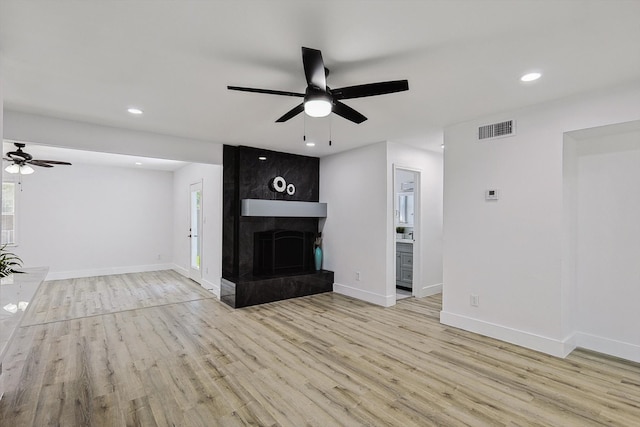 unfurnished living room with a fireplace, ceiling fan, and light hardwood / wood-style flooring