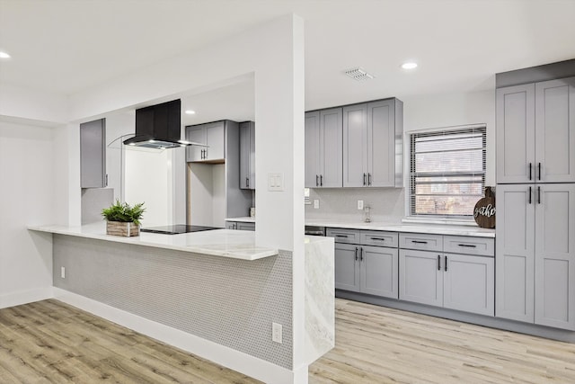 kitchen featuring black electric stovetop, light hardwood / wood-style floors, kitchen peninsula, gray cabinetry, and extractor fan