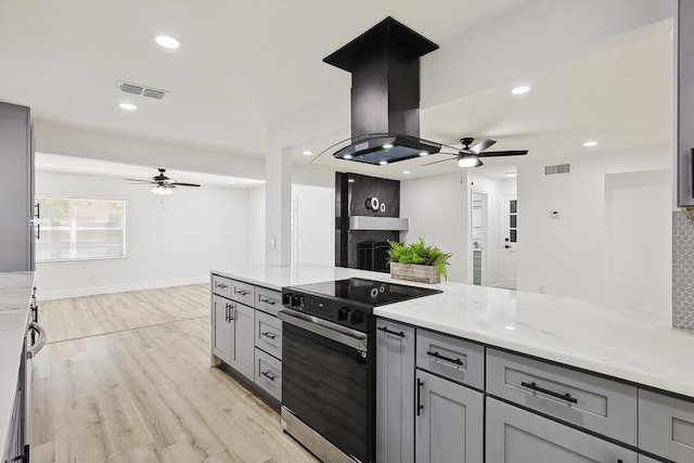 kitchen with gray cabinets, light stone counters, light hardwood / wood-style floors, backsplash, and stainless steel electric stove