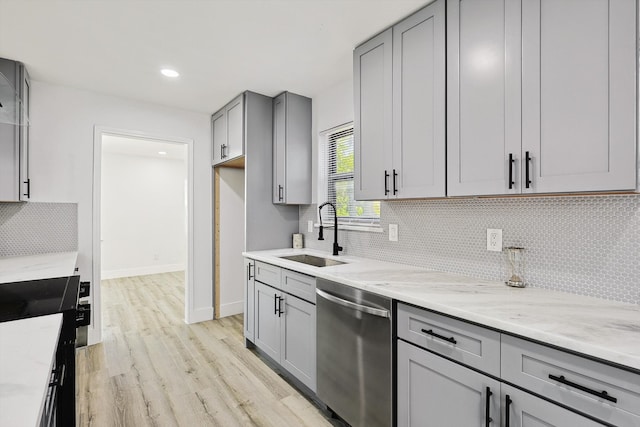 kitchen featuring gray cabinetry, light hardwood / wood-style floors, black stove, stainless steel dishwasher, and sink