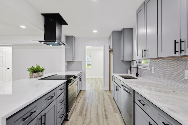 kitchen with gray cabinetry, light hardwood / wood-style floors, stainless steel appliances, ventilation hood, and sink