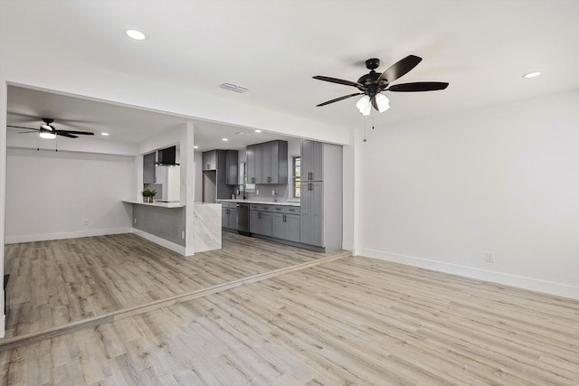 unfurnished living room with ceiling fan, light wood-type flooring, and sink