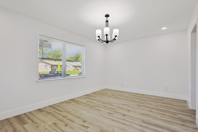 empty room featuring light hardwood / wood-style flooring and a notable chandelier