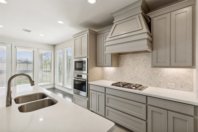 kitchen with custom exhaust hood, stainless steel appliances, sink, and gray cabinetry