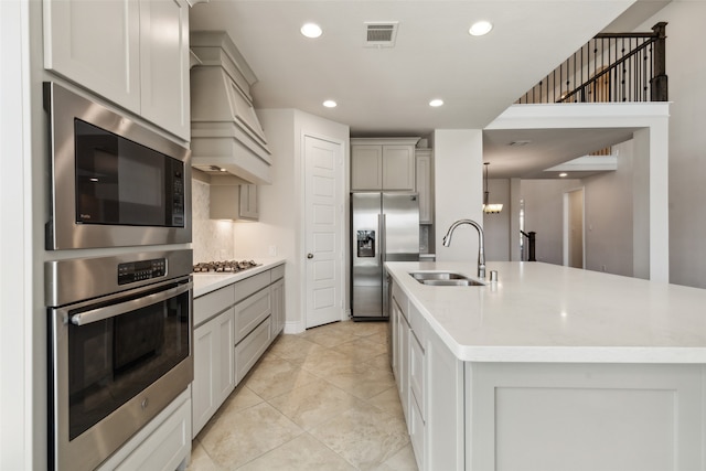 kitchen with premium range hood, light tile patterned floors, sink, a center island with sink, and stainless steel appliances