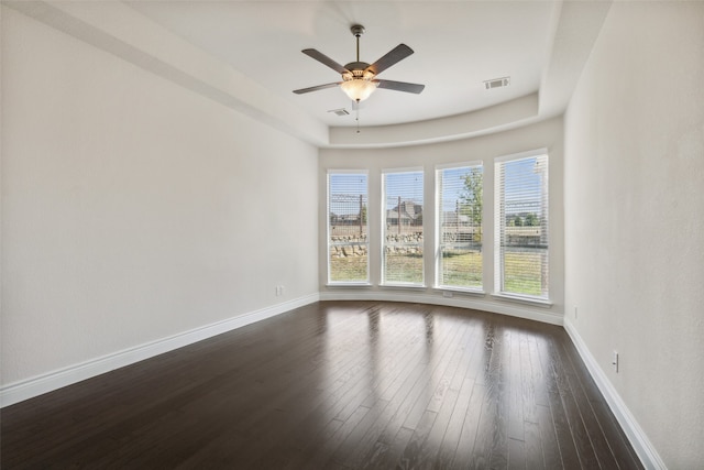 unfurnished room with ceiling fan, a raised ceiling, and dark wood-type flooring