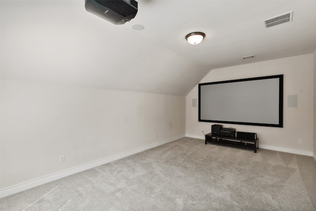 carpeted cinema room featuring vaulted ceiling